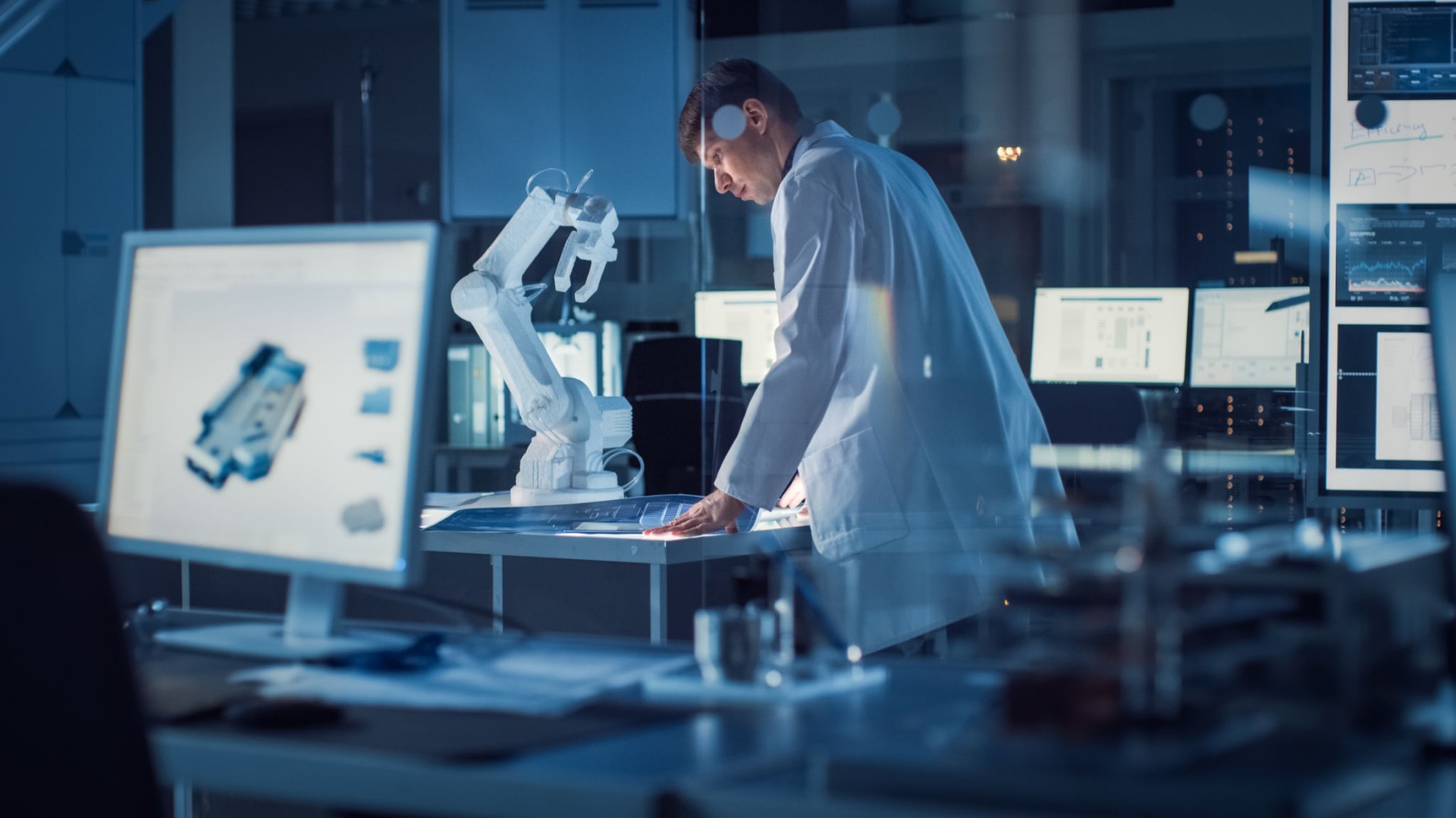 Professional Heavy Industry Robotics Engineer Wearing White Coat Holding Tablet Computer Works in Laboratory. Facility Full of Computers, Various Industrial Design Components and with Robotic Arm